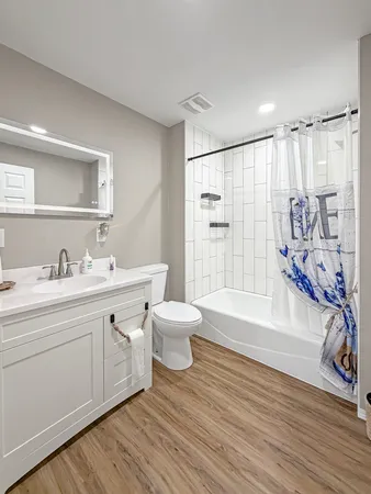a bathroom with a granite countertop sink toilet a large mirror a bathtub and shower