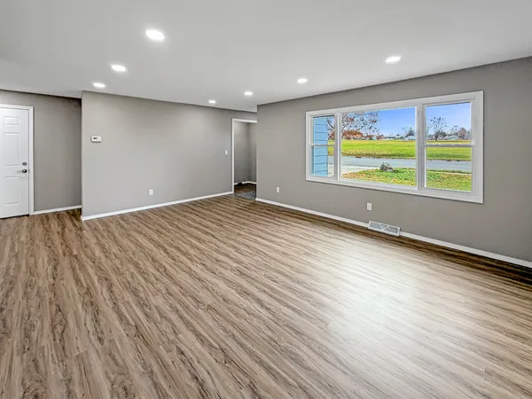 an empty room with wooden floor and windows