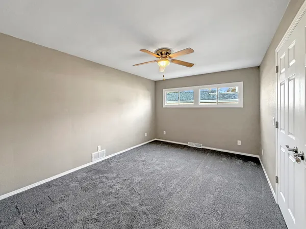 an empty room with a window and a fan