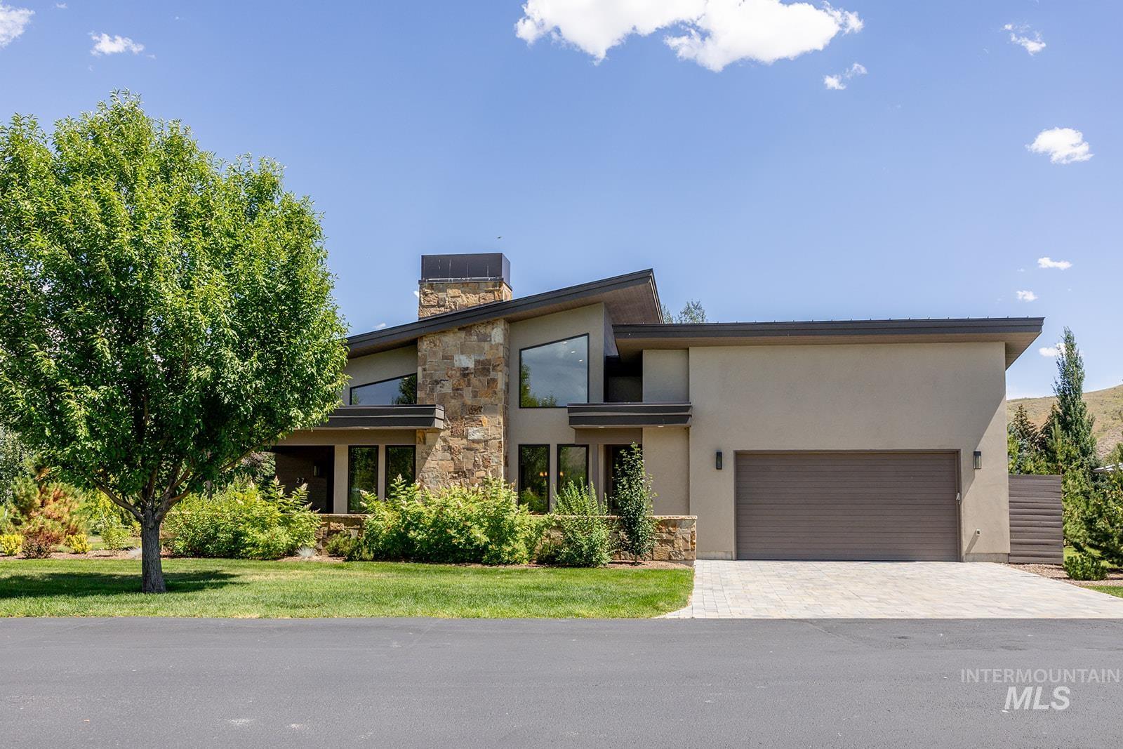 27 Streamside Drive Hailey, ID 83333 - Photo 38 of 39 Contemporary house with stucco siding, an attached garage, stone siding, decorative driveway, and a chimney