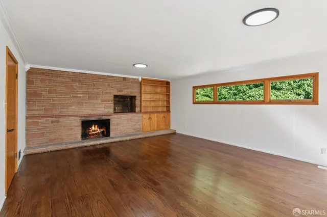 a view of a livingroom with wooden floor and a fireplace