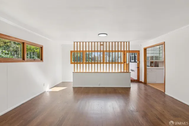 an empty room with wooden floor and windows
