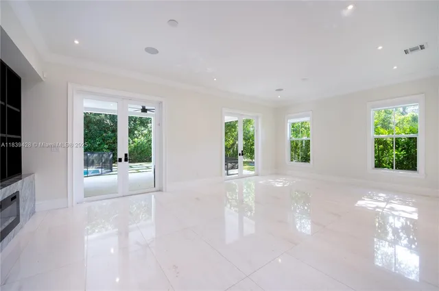 a view of an empty room with a window and kitchen view