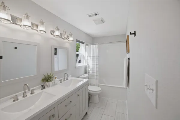 a spacious bathroom with a double vanity sink toilet mirror and shower