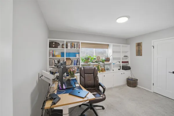 a view of a workspace with furniture and a window