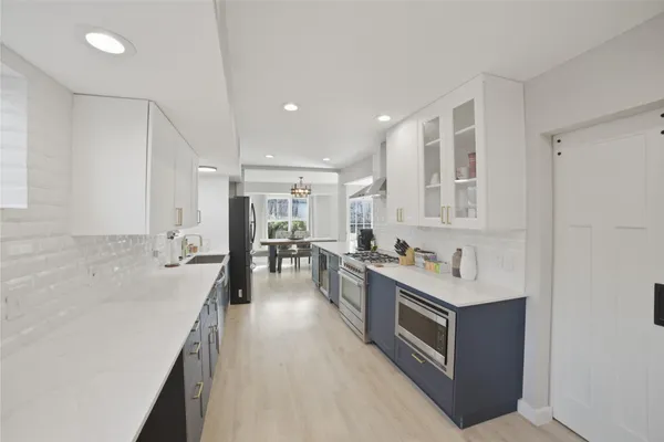 a large white kitchen with a lot of counter space and wooden floor