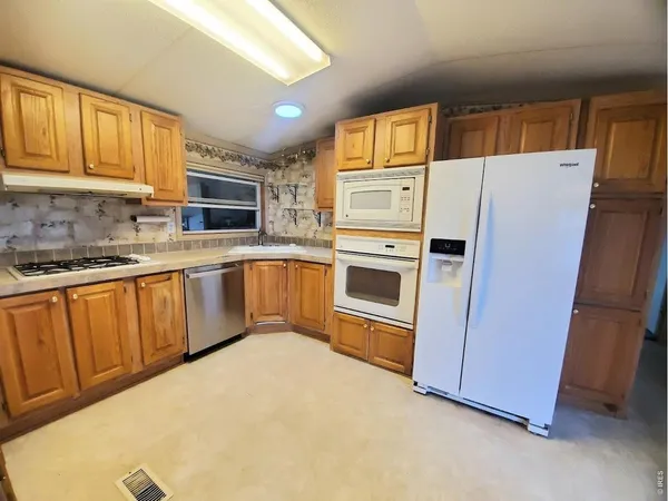a kitchen with stainless steel appliances granite countertop a refrigerator a sink dishwasher a stove with wooden cabinets and floors