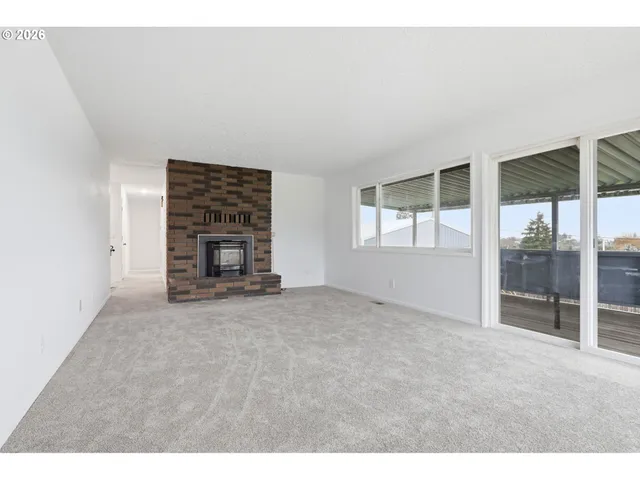 a view of an empty room with fireplace and a window