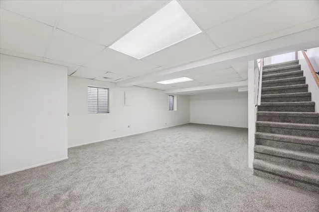 a view of an empty room with stairs and a window