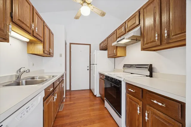 a kitchen with stainless steel appliances granite countertop a sink and dishwasher a stove top oven with wooden floor
