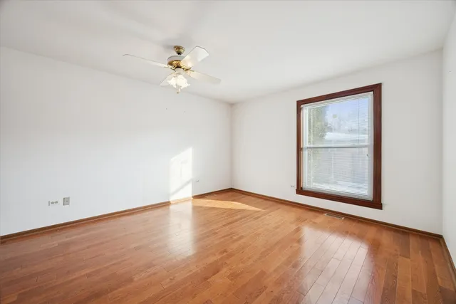 an empty room with wooden floor fan and windows