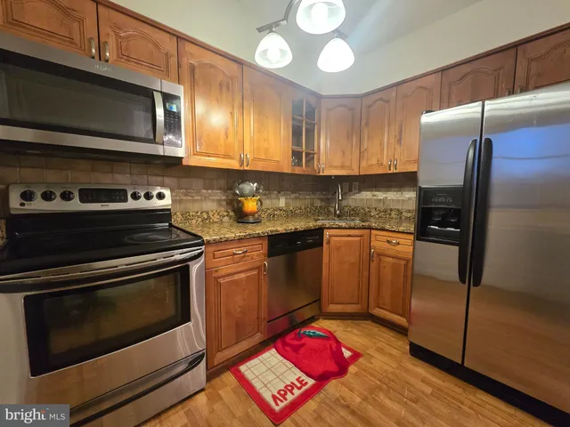 a kitchen with stainless steel appliances granite countertop a stove microwave and refrigerator