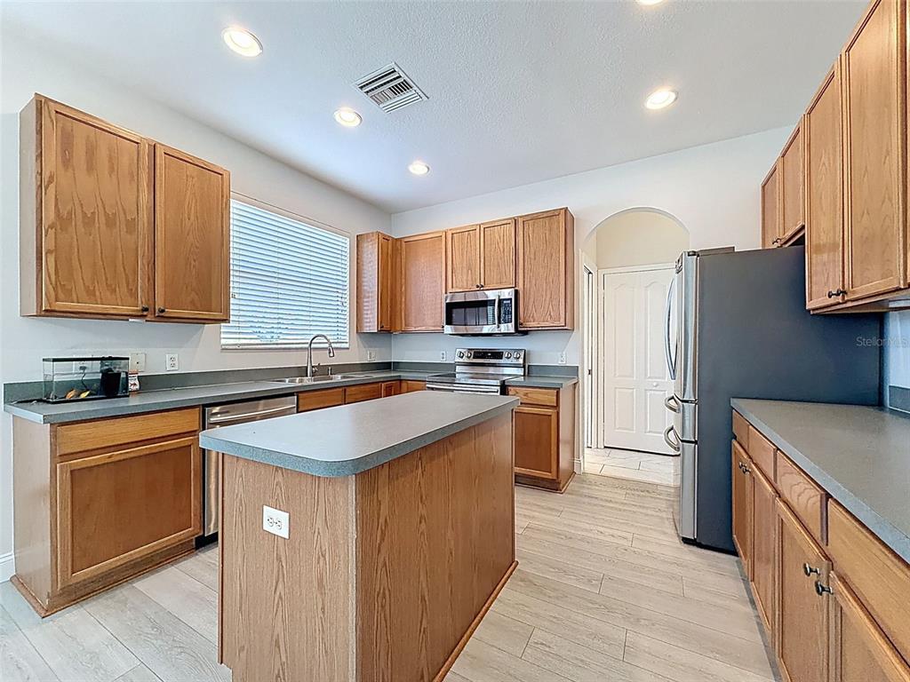 3311 Sisal Loop Wesley Chapel, FL 33544 - Photo 11 of 85 a kitchen with stainless steel appliances granite countertop wooden cabinets a sink a stove a refrigerator and with wooden cabinets