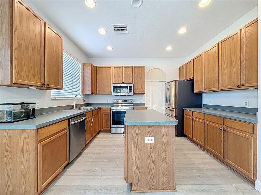 3311 Sisal Loop Wesley Chapel, FL 33544 - Photo 15 of 85 a kitchen with kitchen island granite countertop wooden cabinets stainless steel appliances a sink and a center island