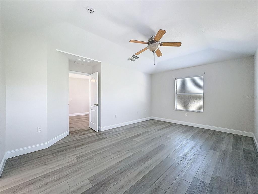 3311 Sisal Loop Wesley Chapel, FL 33544 - Photo 52 of 85 an empty room with wooden floor ceiling fan and windows