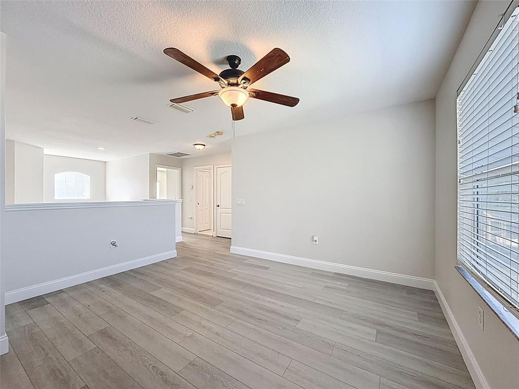 3311 Sisal Loop Wesley Chapel, FL 33544 - Photo 56 of 85 an empty room with wooden floor a ceiling fan and windows