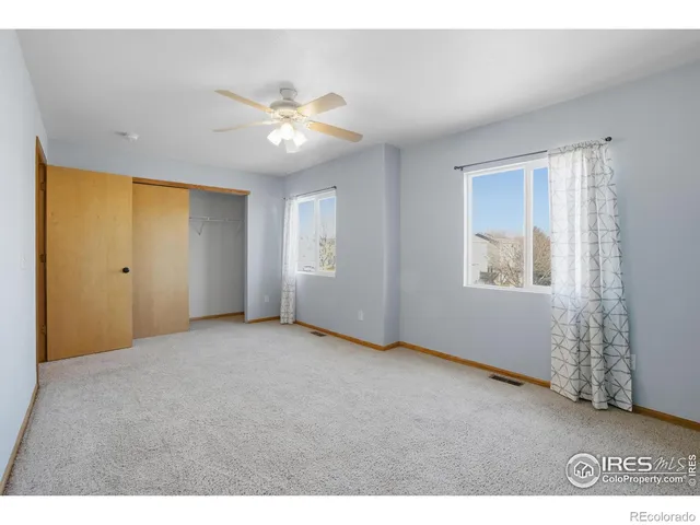 a view of an empty room with window and chandelier fan
