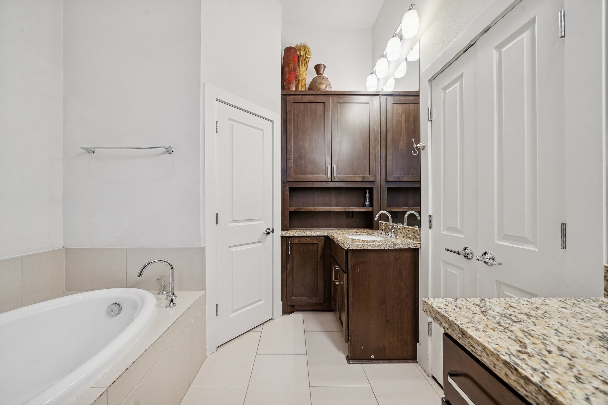 2105 Mason Street Houston, TX 77006 - Photo 15 of 43 This view highlights the vanity area with a granite counter and a built-in cabinet tower for extra storage right where you need it. Bright vanity lighting and a large mirror keep the space functional for getting ready. The clean finishes and simple layout make it easy to maintain.