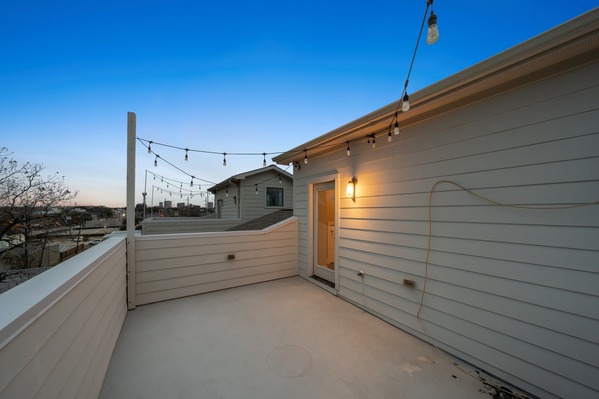 2105 Mason Street Houston, TX 77006 - Photo 18 of 43 Another angle of the rooftop terrace showing the scale of the outdoor space and the warm evening glow from the exterior light. String lights add a finished touch for nighttime ambiance.