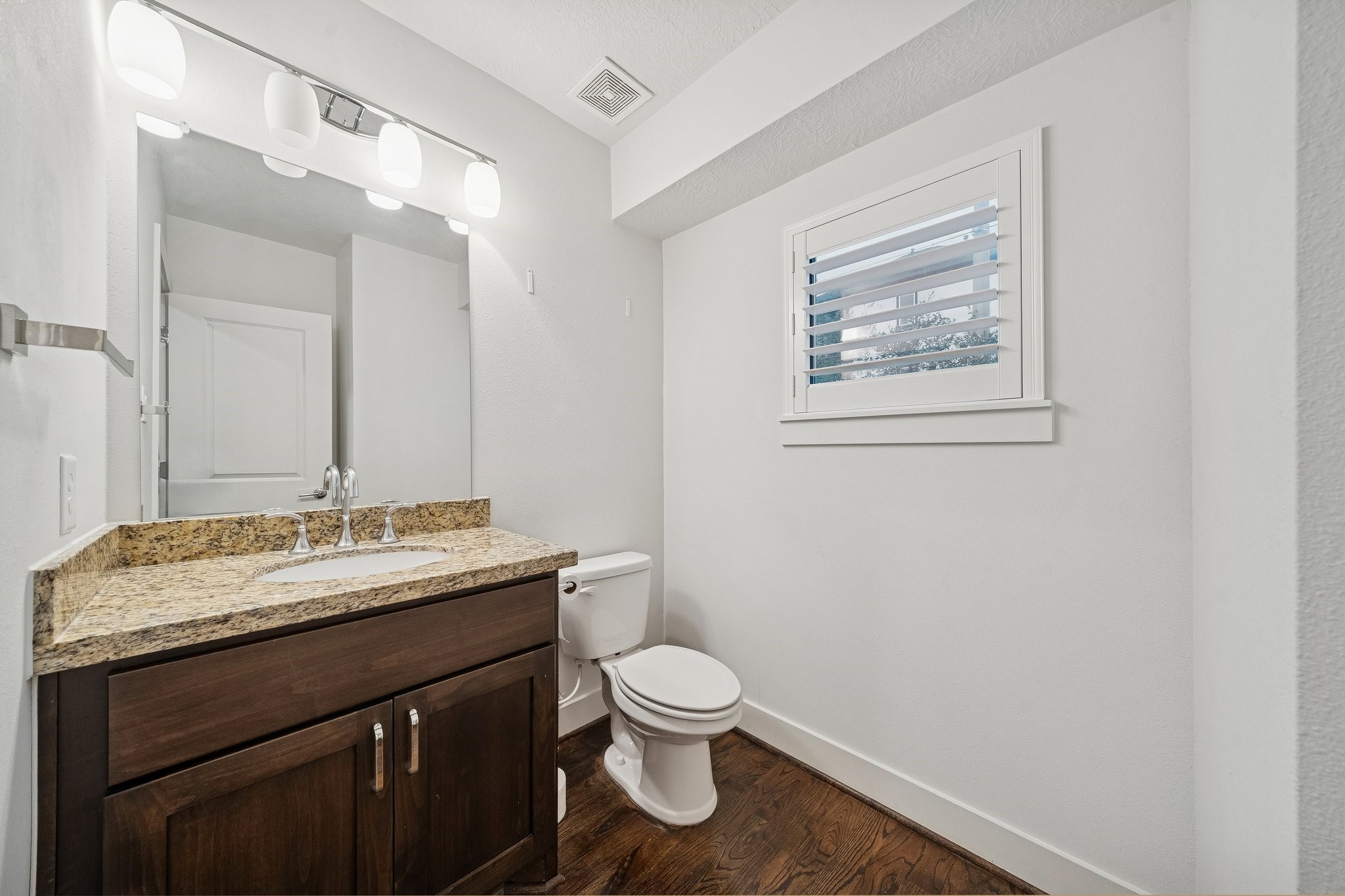 2105 Mason Street Houston, TX 77006 - Photo 24 of 43 Main-level half bath featuring a granite vanity, updated lighting, and a window with plantation shutters for natural light.