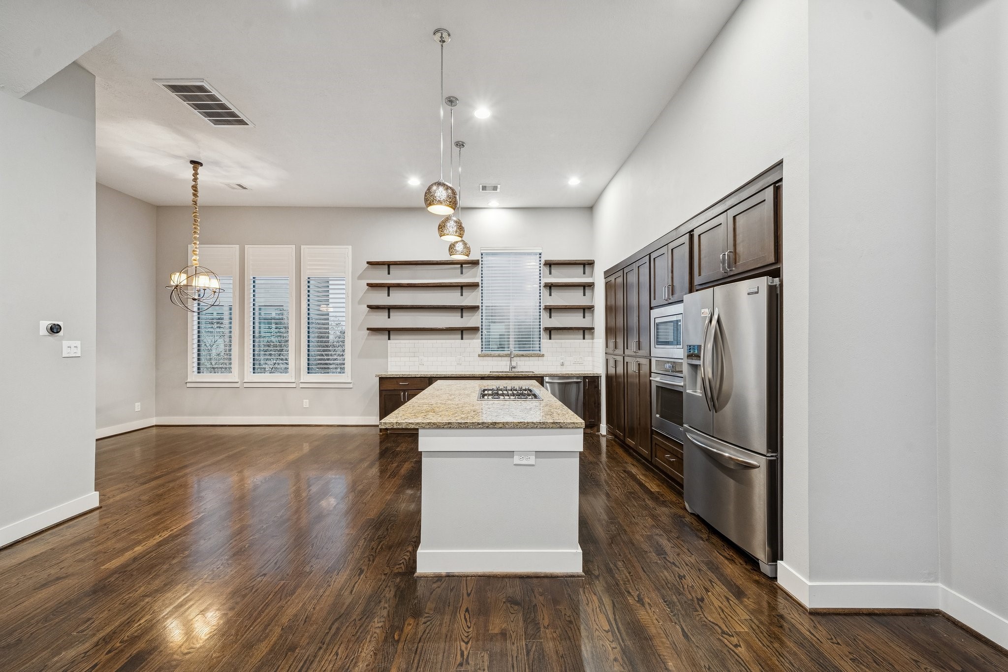 2105 Mason Street Houston, TX 77006 - Photo 28 of 43 This angle highlights the sink wall with a window above it, plus open wood shelving that keeps frequently used items within reach. A white subway-style backsplash brightens the workspace and ties in with the light trim. The island sits close enough to feel conversational, without crowding the perimeter counters.