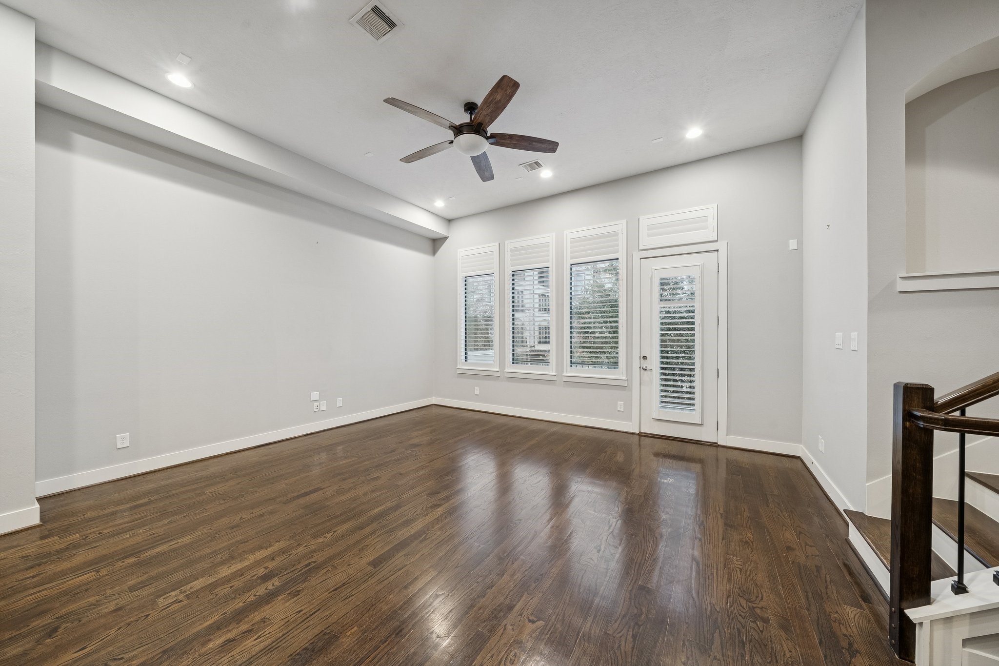 2105 Mason Street Houston, TX 77006 - Photo 30 of 43 Rich-toned hardwoods run wall-to-wall in the living room, giving the space a clean, polished feel. Three tall windows plus a glass-panel door keep the room bright, and recessed lighting with a ceiling fan rounds out the everyday comfort. The shape of the room keeps walkways simple and makes the space feel easy to live in.