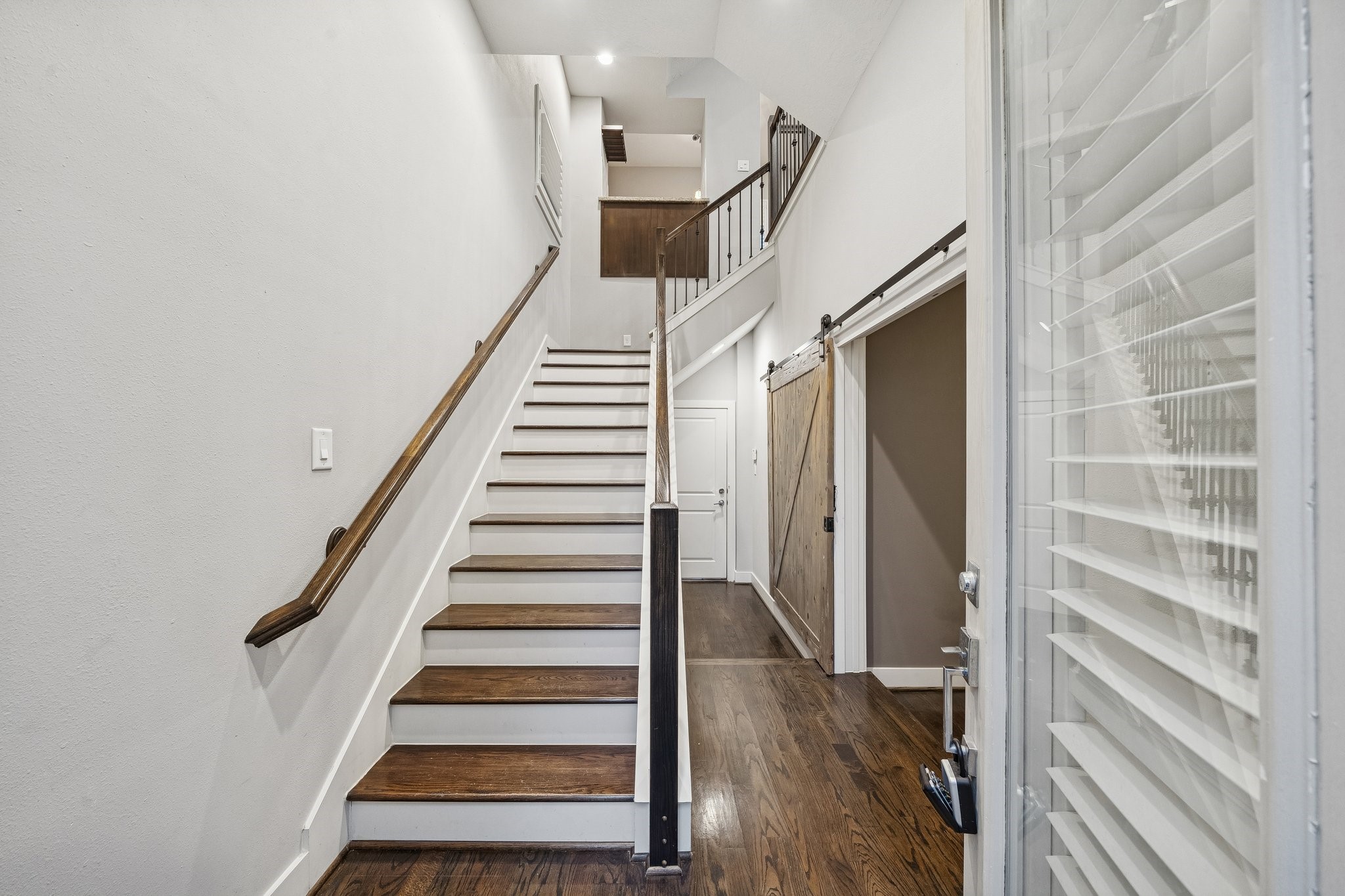2105 Mason Street Houston, TX 77006 - Photo 3 of 43 Bright entry with hardwood floors and a clean, modern staircase featuring contrasting treads and sleek railing details. The open sightline up to the next level adds to the airy feel, with thoughtful finishes that set the tone from the moment you walk in.