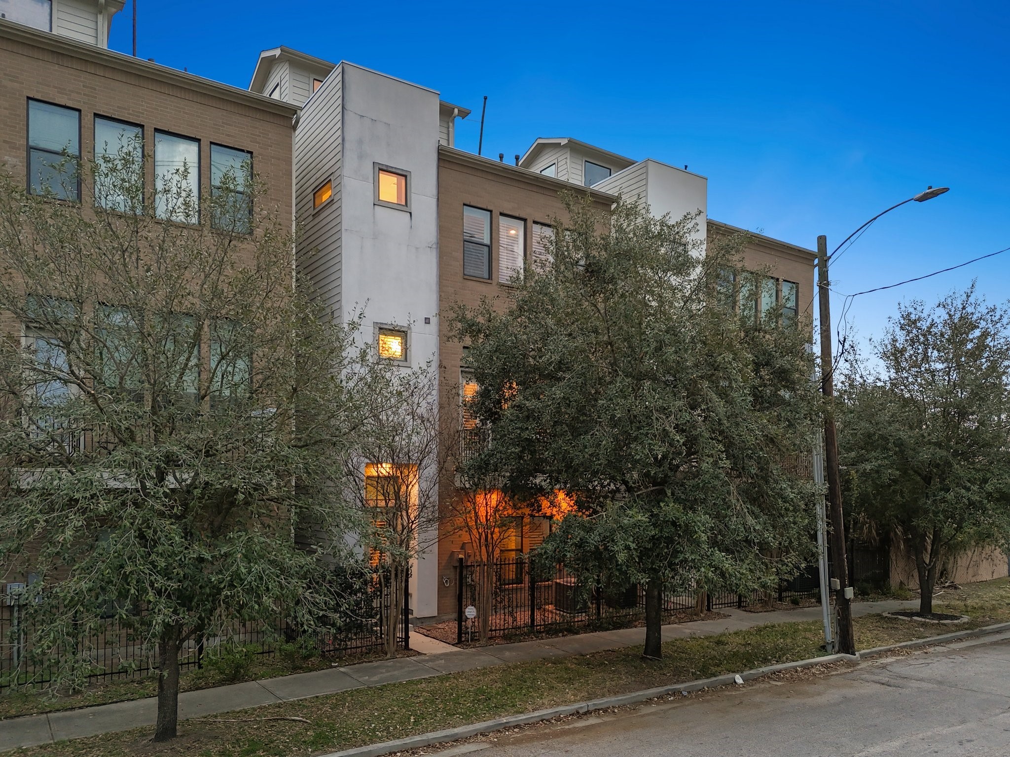2105 Mason Street Houston, TX 77006 - Photo 34 of 43 Evening curb appeal shines as warm interior light spills through oversized windows, highlighting the home’s modern design and multi-level layout. Set along a quiet, tree-lined stretch of Montrose, it feels tucked away while still minutes from the city’s best dining, shopping, and Downtown.