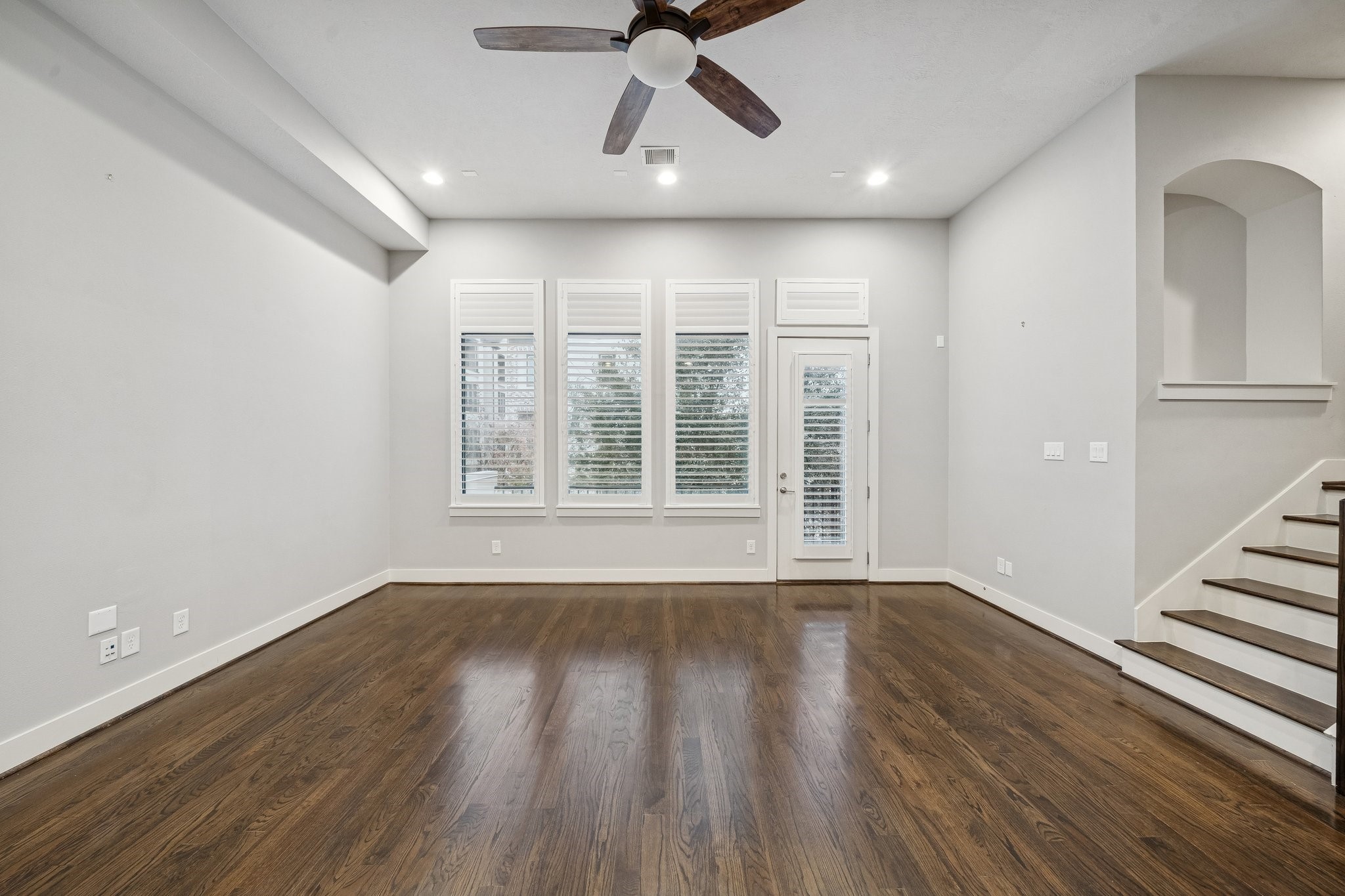 2105 Mason Street Houston, TX 77006 - Photo 8 of 43 Straight ahead, tall windows with shutters line the far wall and pull in natural light without sacrificing privacy. The contrast of light walls and trim against the dark hardwood floors reads crisp, and the recessed lights keep the room evenly lit after sunset. A nearby arched niche adds a little character and a natural spot for artwork or décor.