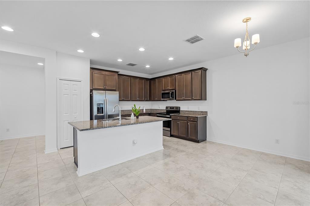 37820 Beacon Brick Drive Zephyrhills, FL 33540 - Photo 10 of 26 a kitchen with granite countertop a stove top oven a sink dishwasher a refrigerator and a dining table with wooden floor