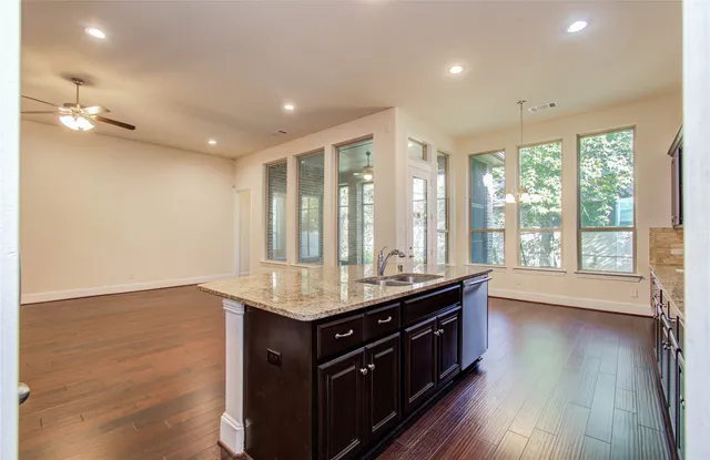 a view of a kitchen with kitchen island granite countertop wooden floors and stainless steel appliances