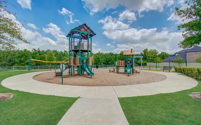 a childrens park with lots of swings slides and swimming pool in the back