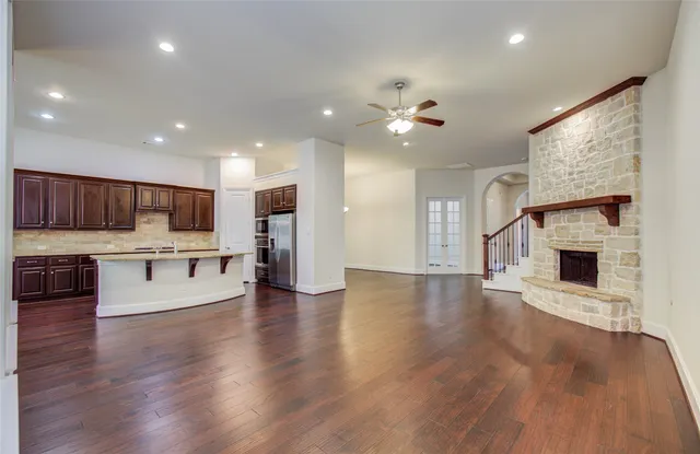 an empty room with wooden floor fireplace and window