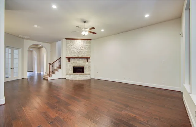 an empty room with wooden floor chandelier fan and entryway