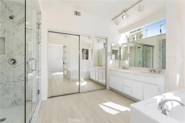 a large bathroom with a glass shower door and a sink