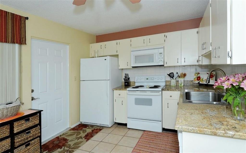2946 Clark Road, Unit 2946 Sarasota, FL 34231 - Photo 3 of 34 a kitchen with stainless steel appliances granite countertop a refrigerator sink and white cabinets
