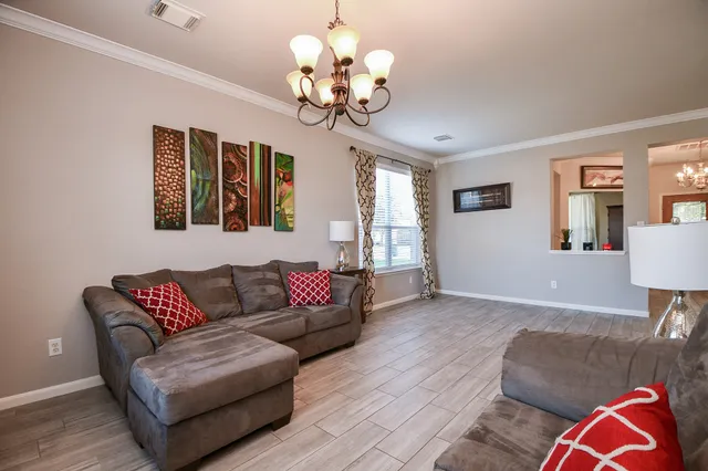 a living room with couch chandelier and a wooden floor