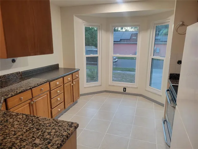 a kitchen with granite countertop a sink a stove and cabinets
