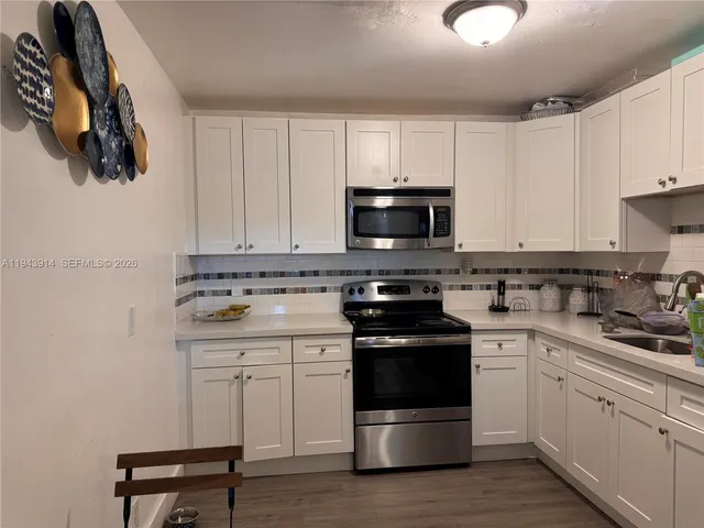 a kitchen with white cabinets stainless steel appliances and sink