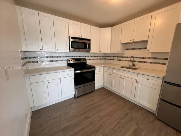 a kitchen with white cabinets appliances and sink
