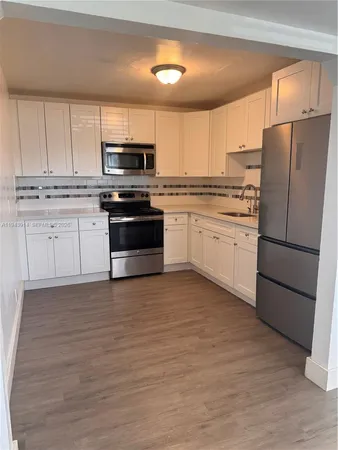 a kitchen with granite countertop a refrigerator stove top oven and sink