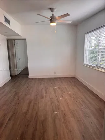 an empty room with wooden floor fan and windows