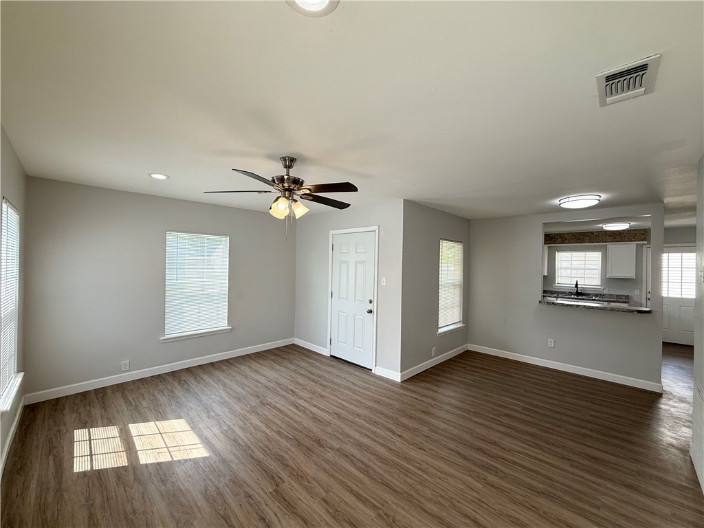 4814 Easter Drive Corpus Christi, TX 78415 - Photo 4 of 19 an empty room with wooden floor chandelier fan and windows
