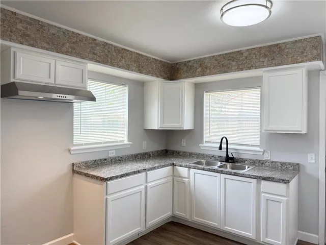 a kitchen with granite countertop cabinets sink and window