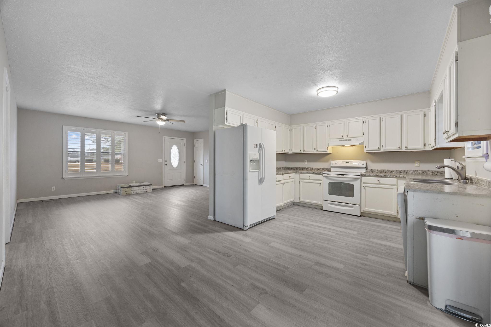5180 Graham Street Loris, SC 29569 - Photo 28 of 28 Kitchen with white appliances, open floor plan, light countertops, a ceiling fan, and white cabinetry