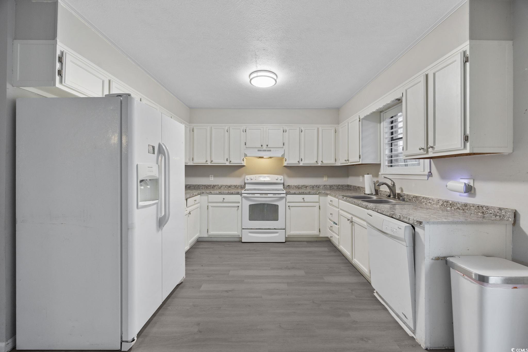 5180 Graham Street Loris, SC 29569 - Photo 12 of 28 Kitchen with white appliances, white cabinetry, light countertops, light wood finished floors, and a textured ceiling