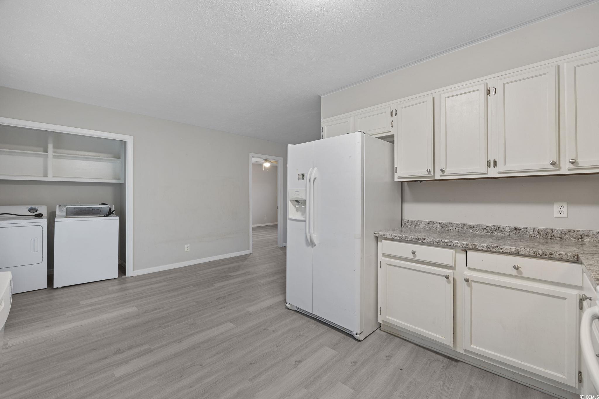 5180 Graham Street Loris, SC 29569 - Photo 14 of 28 Kitchen featuring white fridge with ice dispenser, white cabinets, light countertops, light wood-type flooring, and independent washer and dryer