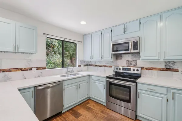 a kitchen with cabinets appliances a sink and a window