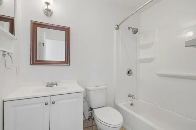 a bathroom with a toilet sink vanity tub and shower