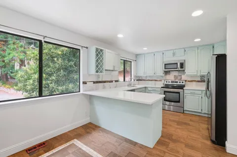 a kitchen with a sink a counter top space stainless steel appliances cabinets and a large window
